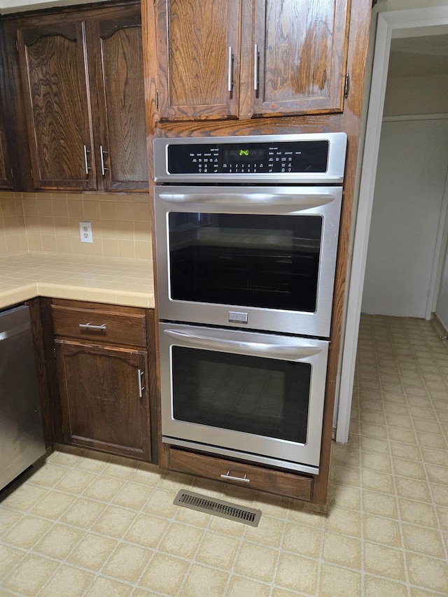 kitchen with visible vents, backsplash, tile counters, light floors, and appliances with stainless steel finishes