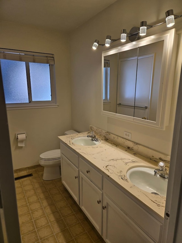 full bathroom with double vanity, visible vents, toilet, and a sink