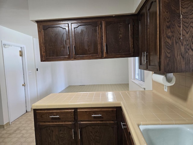 kitchen featuring dark brown cabinetry, light floors, and tile counters