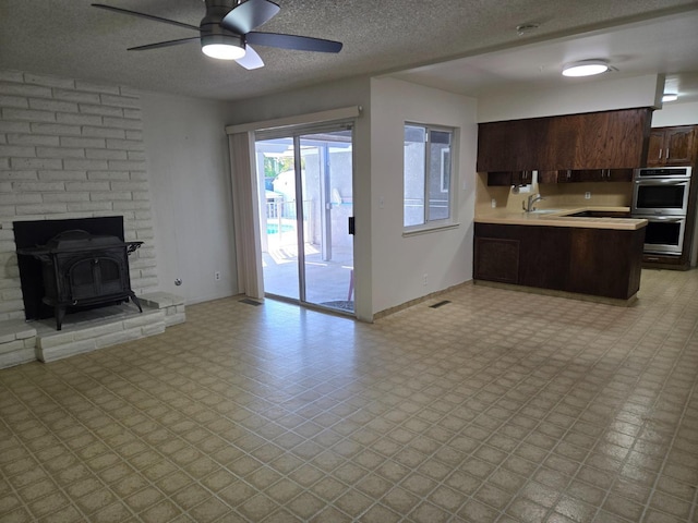 kitchen with open floor plan, light floors, stainless steel double oven, and a sink