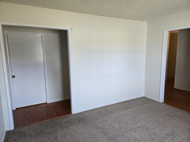 unfurnished bedroom featuring carpet flooring, baseboards, a closet, and a textured ceiling