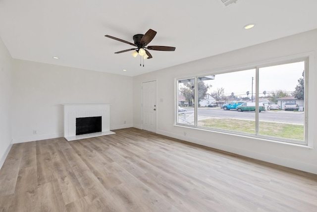 unfurnished living room with ceiling fan, a fireplace, light wood-style floors, and baseboards