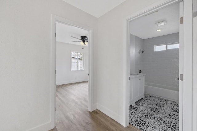 bathroom featuring ceiling fan, wood finished floors, baseboards, and shower / bath combination