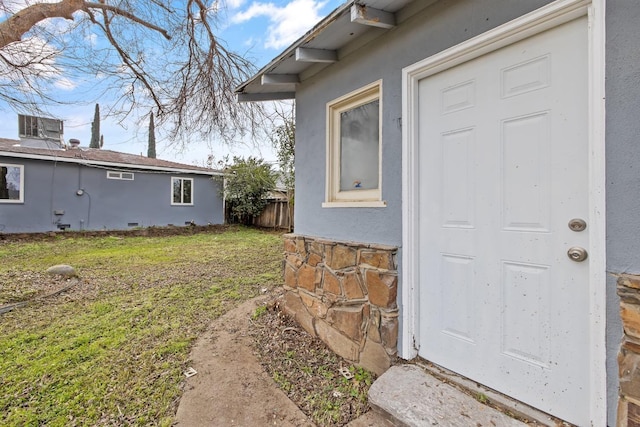 view of exterior entry featuring a yard and stucco siding