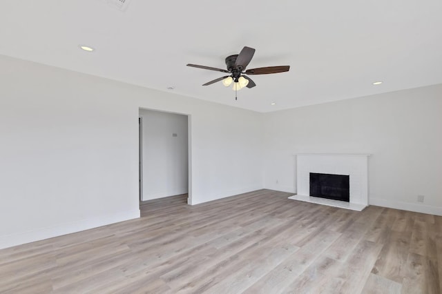 unfurnished living room featuring recessed lighting, baseboards, a brick fireplace, and light wood-style flooring