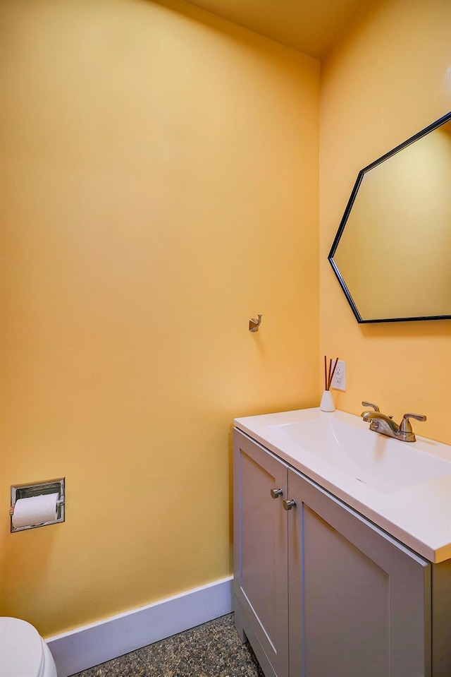 bathroom featuring toilet, vanity, and baseboards