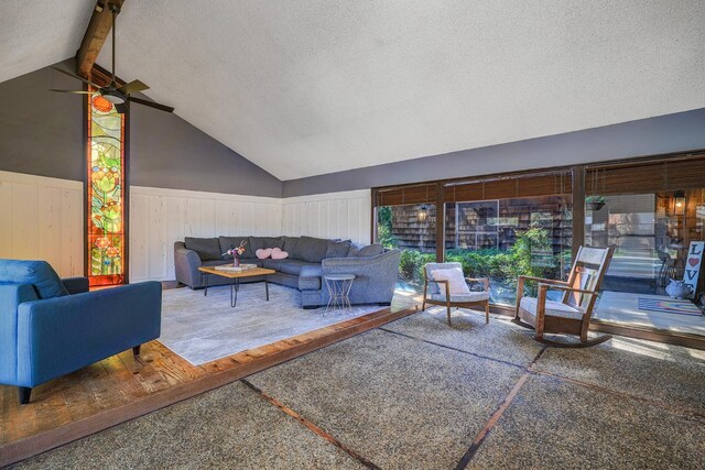 interior space with vaulted ceiling with beams, a ceiling fan, wainscoting, and a textured ceiling