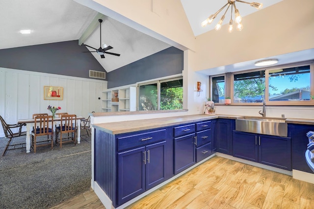 kitchen featuring visible vents, ceiling fan with notable chandelier, light wood-style floors, blue cabinets, and a sink