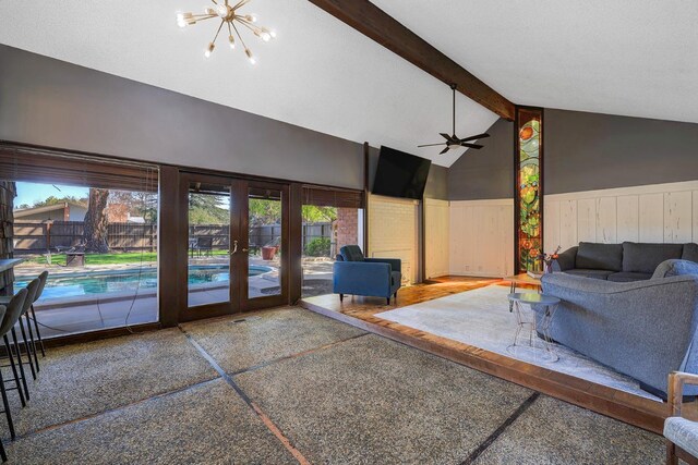 living area featuring beam ceiling, high vaulted ceiling, french doors, wainscoting, and a chandelier