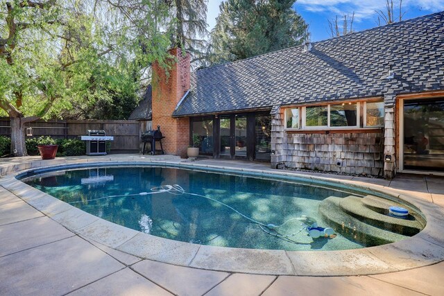 view of pool with a patio, fence, a fenced in pool, and a grill