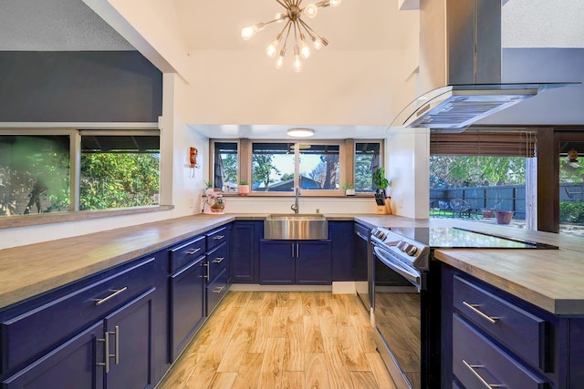 kitchen with island exhaust hood, a sink, electric range oven, butcher block countertops, and blue cabinets