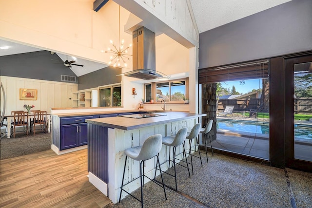 kitchen with island range hood, visible vents, a peninsula, blue cabinetry, and butcher block counters