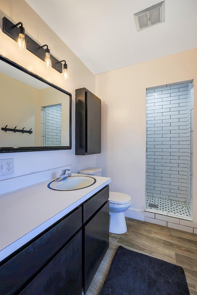 bathroom with visible vents, a shower stall, toilet, wood finished floors, and vanity