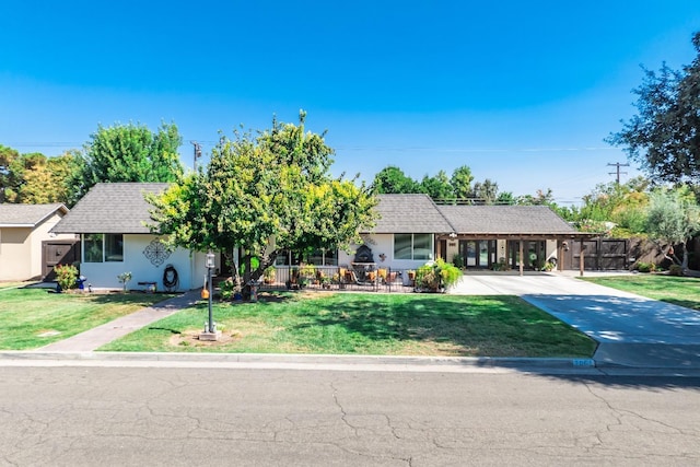 ranch-style house with a front yard, concrete driveway, fence, and roof with shingles