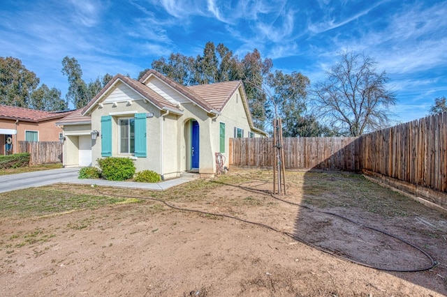 exterior space featuring a tiled roof, fence, and stucco siding