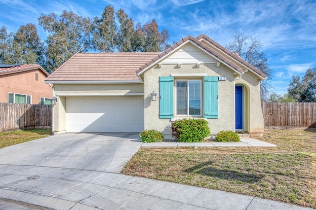 view of front of house with concrete driveway, an attached garage, fence, and a front yard