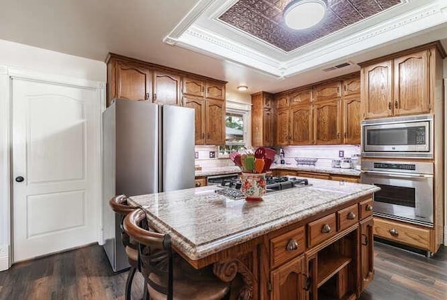 26189 Valerie Ave, Madera, CA 93638 - kitchen with stainless steel appliances, a raised ceiling, brown cabinetry, and a kitchen island