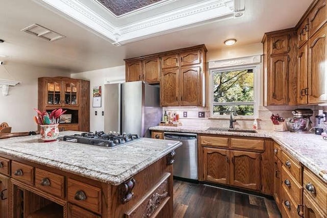 26189 Valerie Ave, Madera, CA 93638 - kitchen featuring appliances with stainless steel finishes, a sink, dark wood-style flooring, a center island, and brown cabinetry