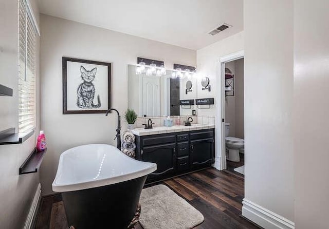 26189 Valerie Ave, Madera, CA 93638 - full bathroom featuring a soaking tub, wood finished floors, double vanity, and toilet