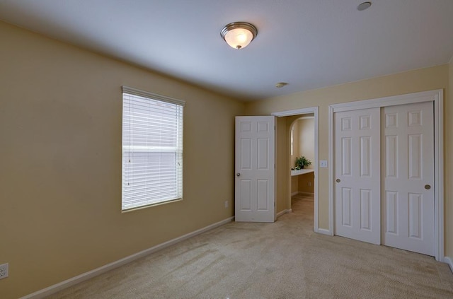 unfurnished bedroom with carpet, a closet, and baseboards