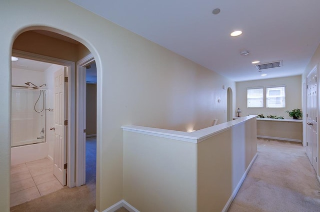 hall featuring arched walkways, visible vents, light carpet, and light tile patterned flooring