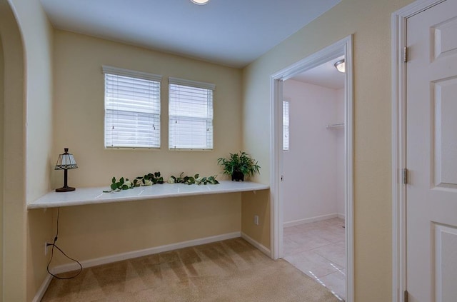 entryway featuring light tile patterned floors, baseboards, arched walkways, and light colored carpet