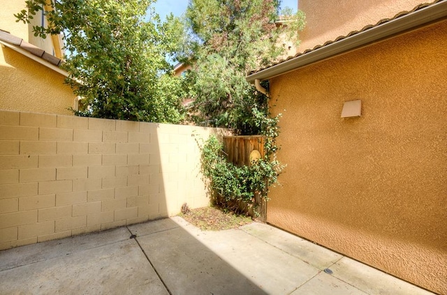 view of side of home with stucco siding, a patio, and fence