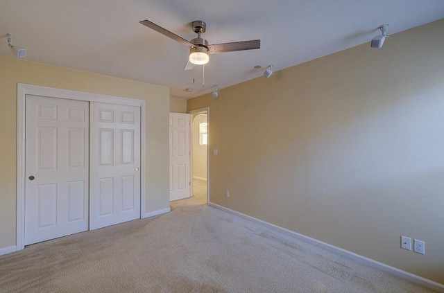 unfurnished bedroom with carpet flooring, baseboards, a closet, and ceiling fan