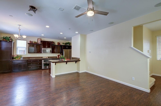 kitchen featuring visible vents, stainless steel appliances, dark wood-type flooring, a kitchen bar, and dark countertops