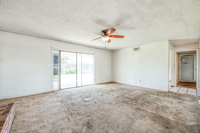 empty room featuring carpet flooring, ceiling fan, a textured ceiling, and visible vents