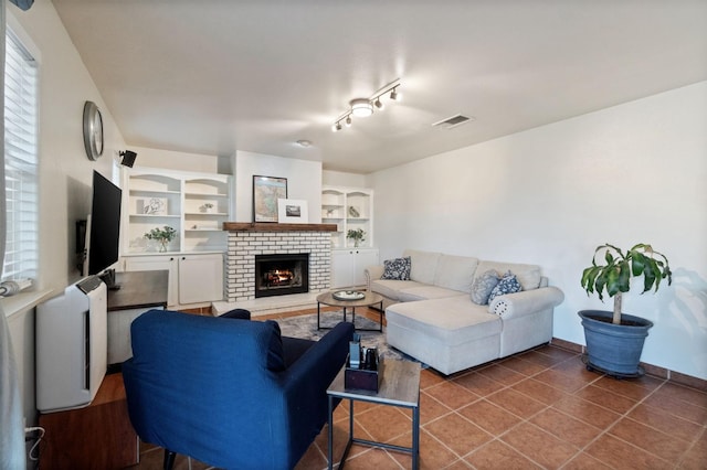 tiled living room with visible vents, a brick fireplace, baseboards, and built in features