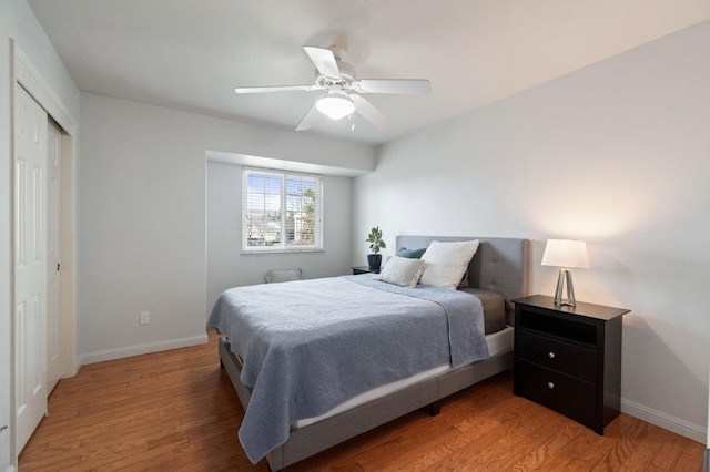 bedroom featuring light wood-type flooring, baseboards, a closet, and a ceiling fan