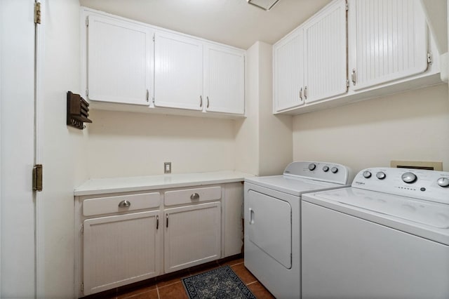 laundry area featuring washer and clothes dryer, cabinet space, and dark tile patterned flooring