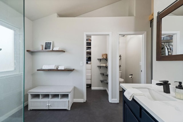 full bath featuring a spacious closet, baseboards, toilet, vaulted ceiling, and vanity