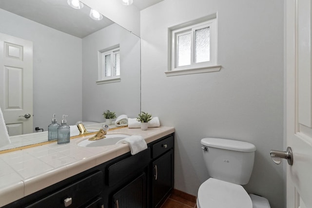 half bath featuring tile patterned flooring, toilet, and vanity