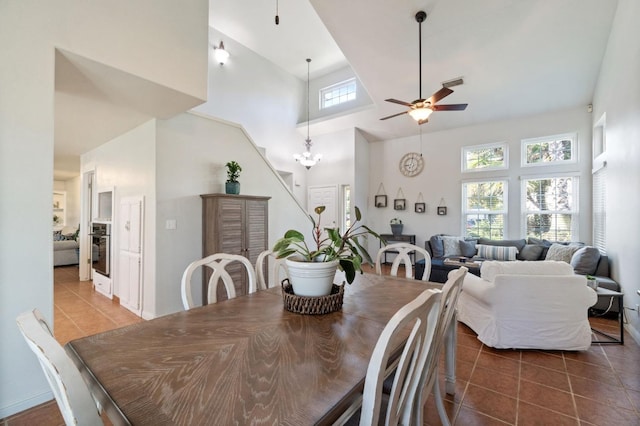 dining room with tile patterned floors, a high ceiling, and ceiling fan with notable chandelier