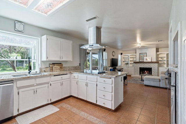 kitchen featuring visible vents, a peninsula, a sink, stainless steel dishwasher, and island range hood