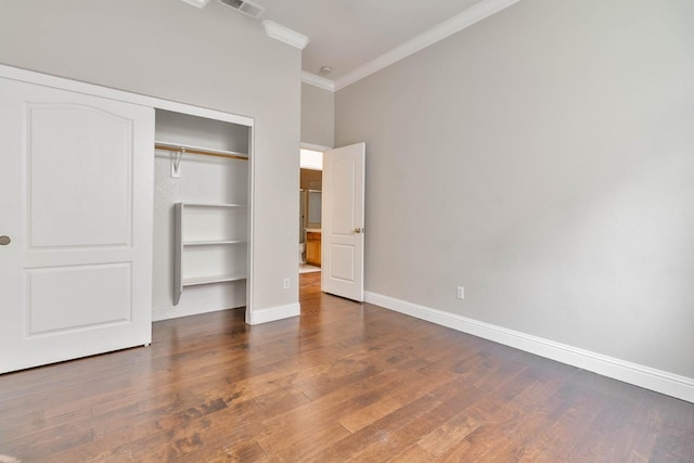 unfurnished bedroom with a closet, wood finished floors, baseboards, and ornamental molding