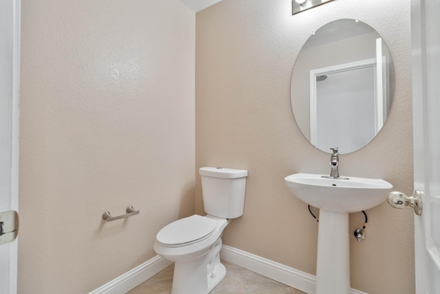 bathroom featuring baseboards, toilet, and tile patterned flooring