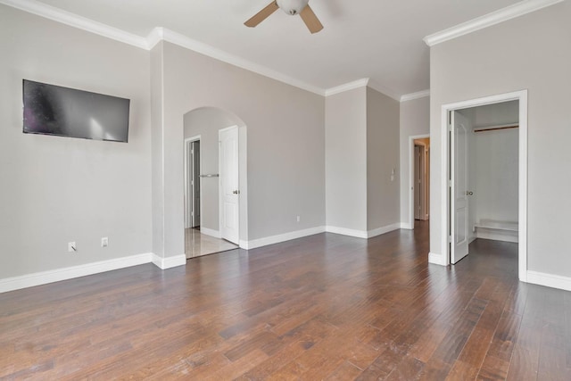 interior space featuring wood finished floors, baseboards, arched walkways, ceiling fan, and crown molding