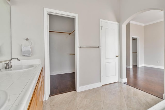 full bathroom featuring a walk in closet, double vanity, baseboards, and a sink