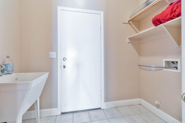 clothes washing area with light tile patterned floors, laundry area, baseboards, and washer hookup