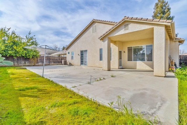 rear view of property with a yard, a patio area, fence, and stucco siding