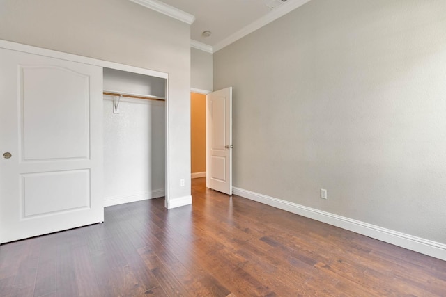 unfurnished bedroom featuring dark wood-style floors, baseboards, a closet, and ornamental molding