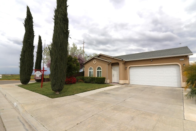 view of front of house with stucco siding, driveway, a front yard, and a garage