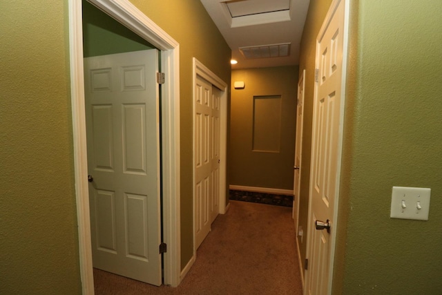 hall with a textured wall, visible vents, and carpet floors