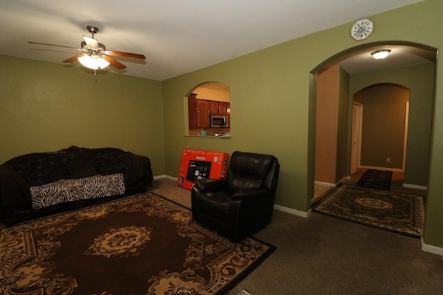 carpeted living area featuring baseboards, arched walkways, and a ceiling fan