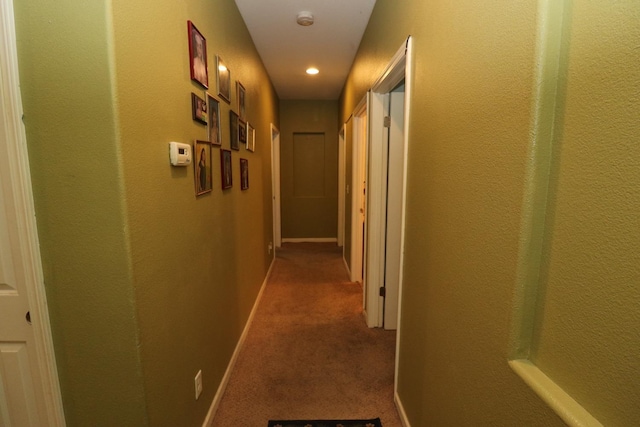 corridor featuring baseboards and carpet floors