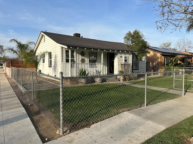 view of front of house featuring a front lawn, covered porch, a fenced front yard, and a shingled roof