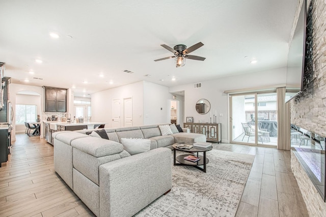 living area featuring recessed lighting, a ceiling fan, arched walkways, and light wood-type flooring